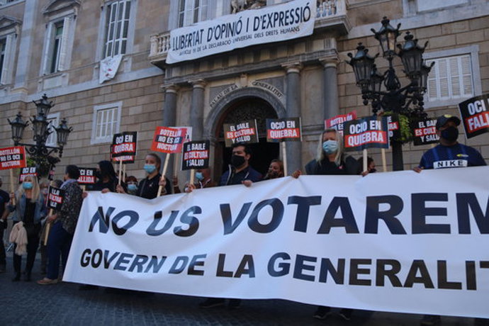Pla obert de diversos treballadors i empresaris de l'oci nocturn exhibint una pancarta de protesta davant el Palau de la Generalitat. Imatge del 5 d'octubre de 2020. (Horitzontal)