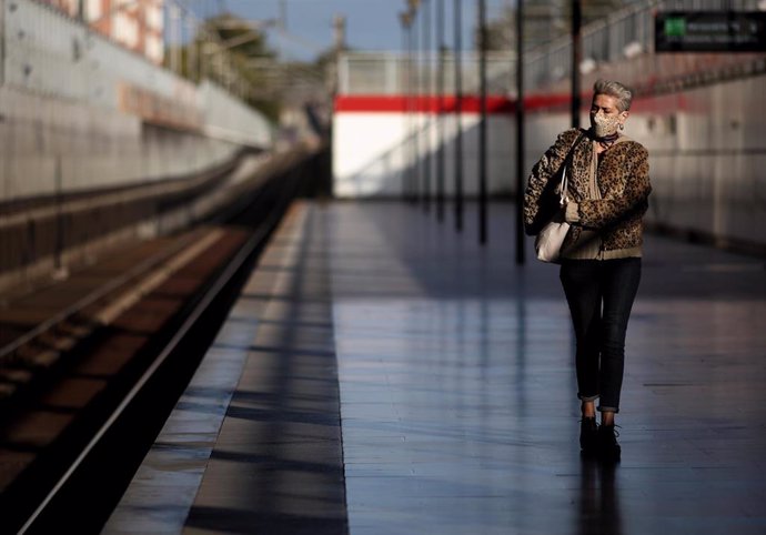 Una mujer espera en un andén de una estación de tren