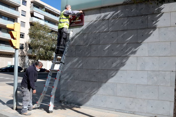 Pla sencer d'un operari damunt d'una escala collocant la placa del carrer Neus Catal de Lleida, el 6 d'octubre del 2020. (Horitzontal)
