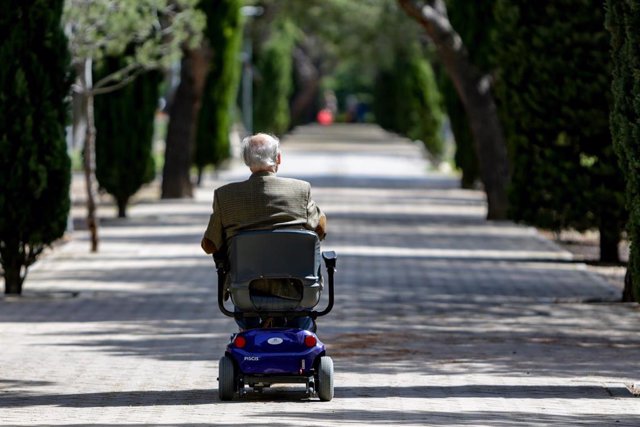 Un anciano en silla de ruedas eléctrica en un parque en el primer día en que los españoles pueden salir de casa a pasear y hacer ejercicio al aire libre, pero solo en determinadas franjas horarias, divididos por edades, en el mismo municipio de residencia