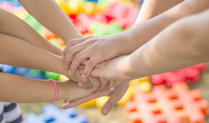 Varios niños entrelazan sus manos en una actividad colaborativa
