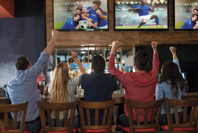 Aficionados viendo un partido de fútbol en las pantallas de televisión de un bar