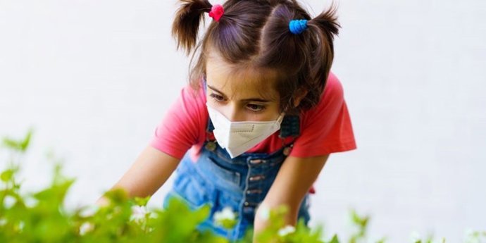 Una niña con una mascarilla juega en la calle