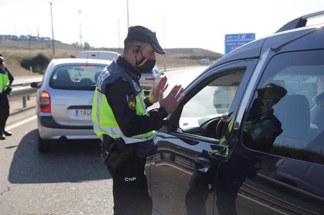 Un agente de la Policía Nacional habla con un conductor en un control policial ante las medidas de restricción de la movilidad en la ciudad de León.