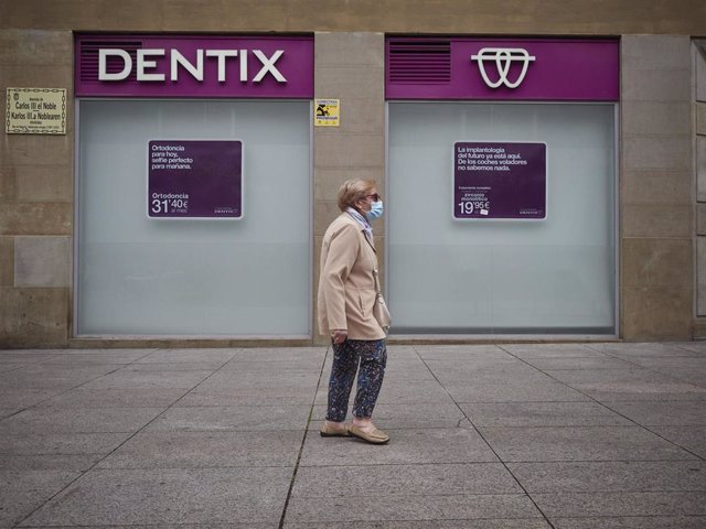 Una mujer pasea enfrente de una clínica.
