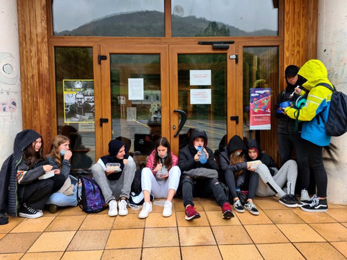 Pla general d'un grup de joves dinant amb carmanyola a la porta de l'Arxiu Comarcal del Pallars Sobir on es resguardaven de la pluja el 2 d'octubre del 2020. (horitzontal)