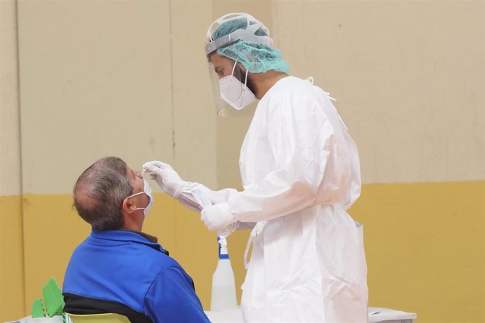 Una sanitaria toma muestras a un hombre a través de un frotis de nariz durante la realización de test de antígenos, foto de archivo