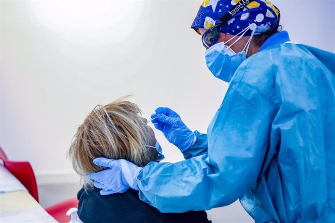 Un sanitario toma muestras a una mujer a través de un frotis de nariz para realizar un test de antígenos en Puente de Vallecas