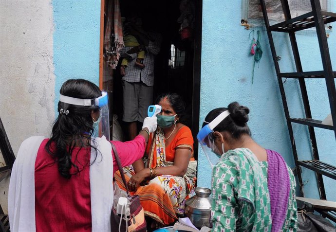 Una trabajadora mide la temperatura corporal de una mujer en India.