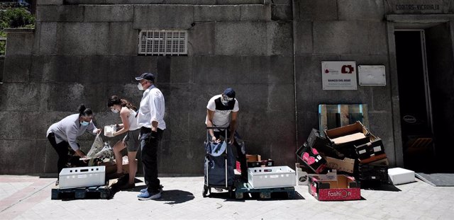 Dos personas recogen alimentos que les dan dos voluntarios a las puertas de la Parroquia Santa María Micaela, en Madrid, el pasado 29 de mayo, en pleno confinamiento por coronavirus.