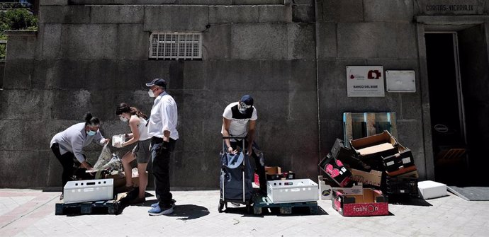 Dos personas recogen alimentos que les dan dos voluntarios a las puertas de la Parroquia Santa María Micaela, en Madrid, el pasado 29 de mayo, en pleno confinamiento por coronavirus.