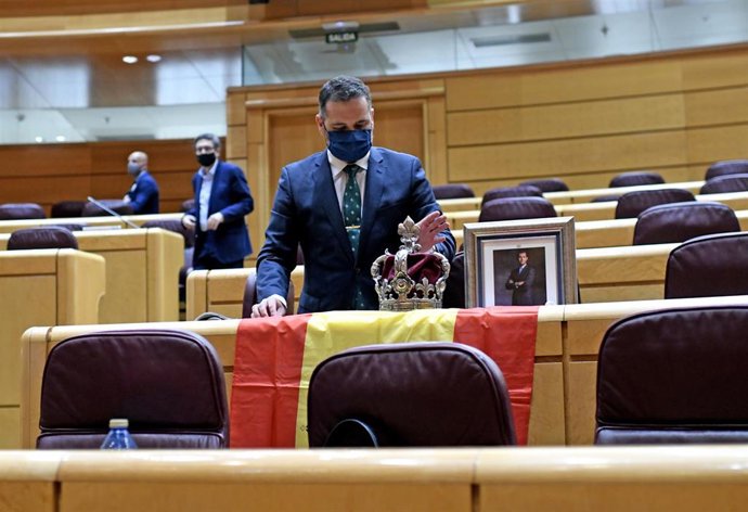 El senador del PP David Muñoz coloca una corona y una foto del Rey en un escaño del Senado el día de la comparecencia del vicepresidente segundo y ministro de Derechos Sociales y Agenda 2030, Pablo Iglesias