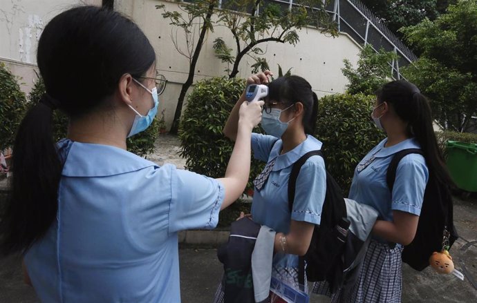 Un grupo de estudiantes de una escuela secundaria de Hong Kong se toman la temperatura antes de entrar a clase.