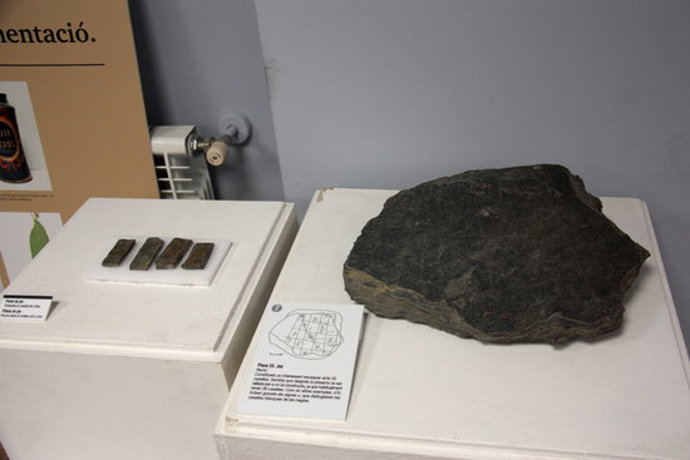 Pla obert d'una de les pissarres gravades del castell de Llívia i de peces que servien per jugar que es poden veure en el marc d'una exposició sobre l'art rupestre de Cerdanya. Imatge del 7 d'octubre de 2020 (Horitzontal).
