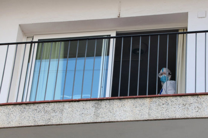Detall del balcó d'una habitació de la residncia Calafell Park de Segur de Calafell, amb un treballador amb EPI sortint per la porta. Imatge del 9 d'octubre del 2020 (horitzontal)