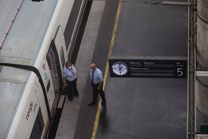 Dos trabajadores conversan junto a un tren en la estación de Atocha