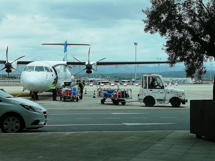 Personal de handling en pista trabajando con un avión interislas en el aeropuerto de Palma.