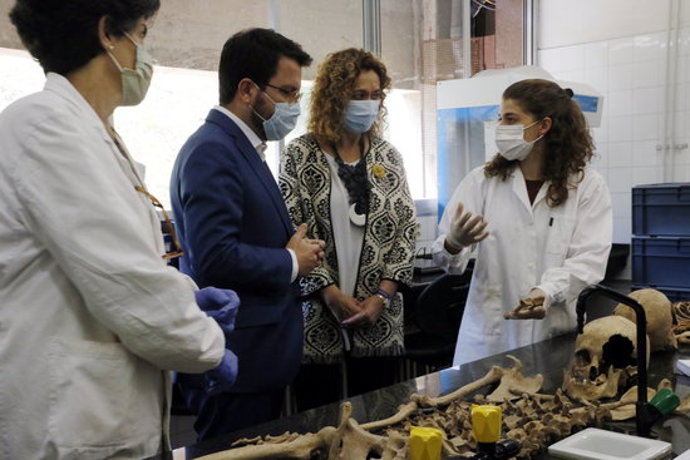 Pla tres quarts de la consellera Capella i el vicepresident Aragons escoltant les explicacions de les investigadores al laboratori de la UAB. Imatge del 9 d'octubre del 2020. (Horitzontal)