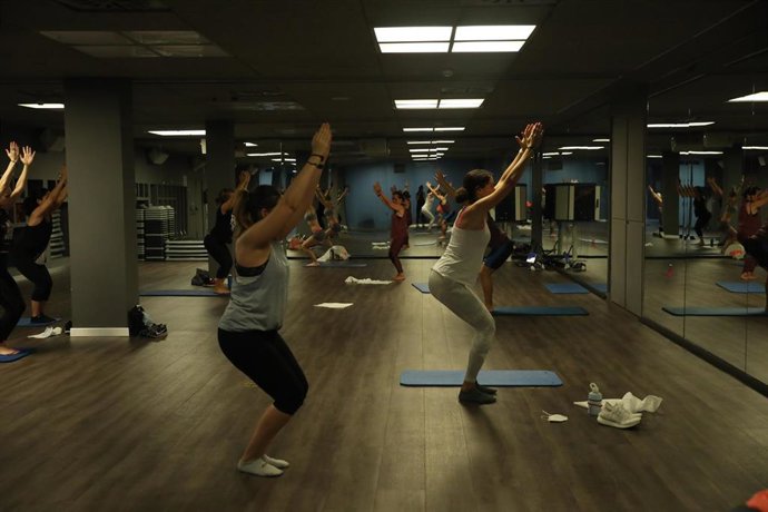 Un entrenador imparte clase a varias personas en una clase de Body Balance en un gimnasio .