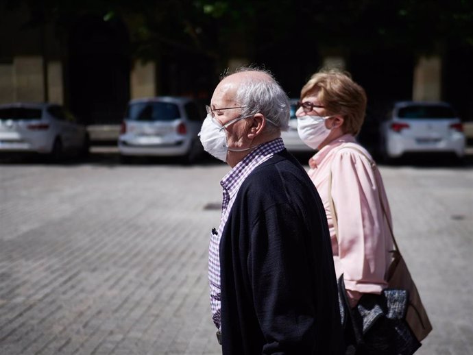 Varias personas mayores con mascarillas pasean por las calles de Pamplona