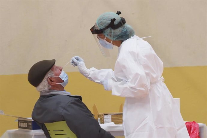 Una sanitaria toma muestras a un hombre a través de un frotis de nariz durante la realización de test de antígenos