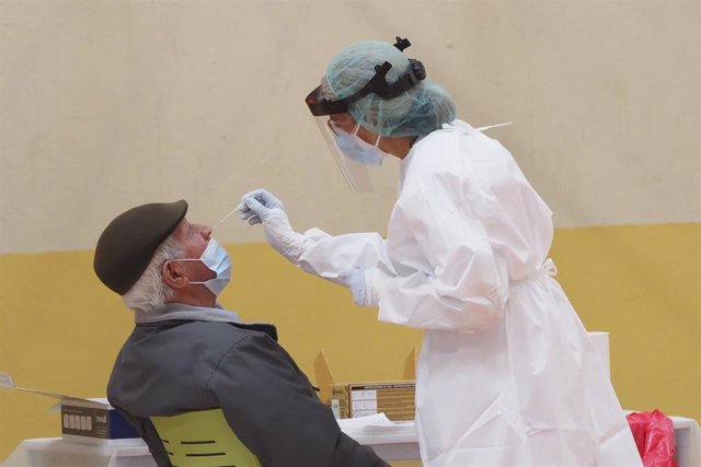 Una sanitaria toma muestras a un hombre a través de un frotis de nariz durante la realización de un test de antígenos , foto de archivo
