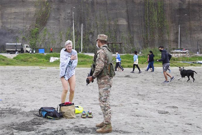 Un soldado peruano pide a una mujer abandonar la playa, que aún permanece cerrada por la pandemia. 