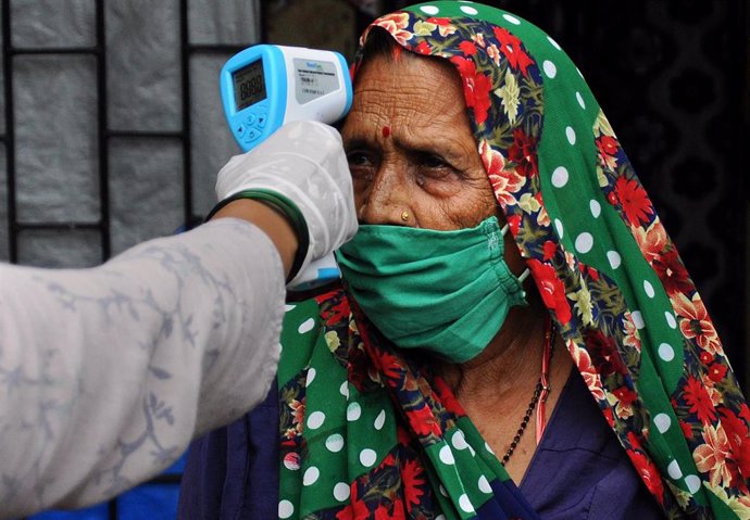 Un trabajador sanitario toma la tempeartura a una mujer en India.