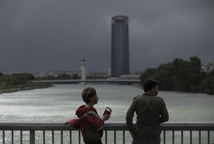 Dues persones caminen pel Pont de la Barqueta a Sevilla (Imatge d'arxiu)