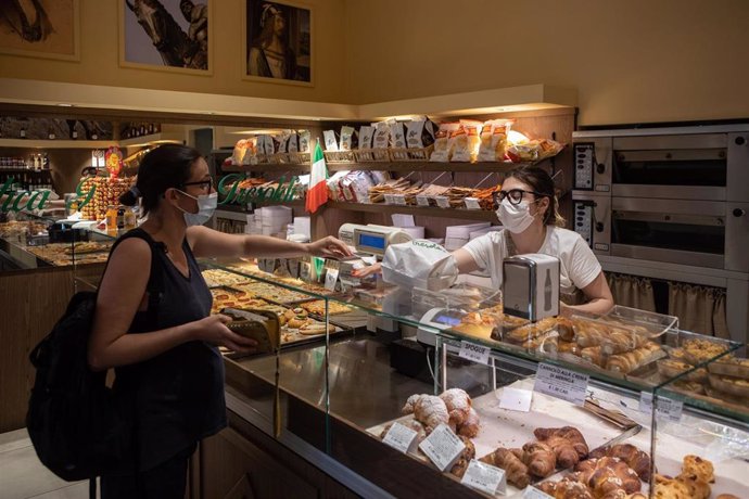 Mujeres con mascarilla en una panadería de Bérgamo, Italia