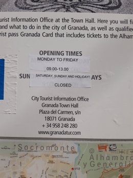 Imagen de un cartel con el horario de la Oficina de Turismo de Granada, cerrada durante el puente .