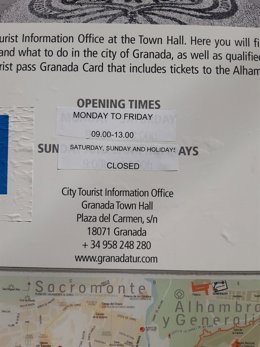 Imagen de un cartel con el horario de la Oficina de Turismo de Granada, cerrada durante el puente .