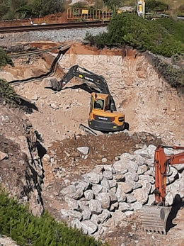 Una excavadora treballa per reparar un esvoranc al tram Vilanova-Sitges de la línia de Rodalies de Renfe R2 sud el 12 d'octubre del 2020. Pla general. (Vertical)