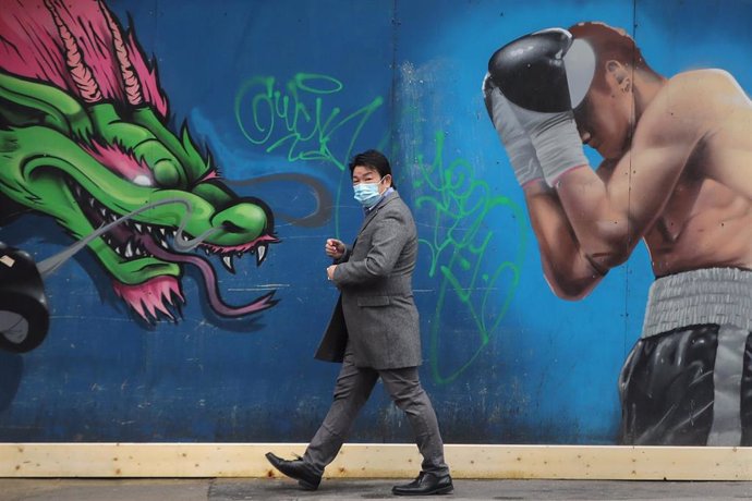 Un hombre con mascarilla pasa ante un mural en Dublín
