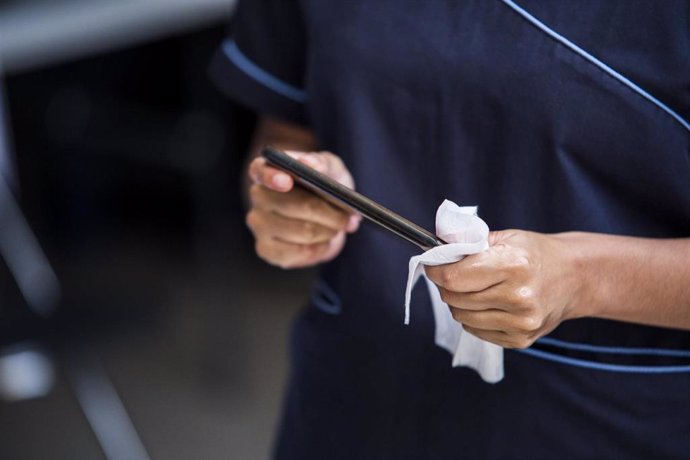 Una persona desinfecta la pantalla de su teléfono móvil