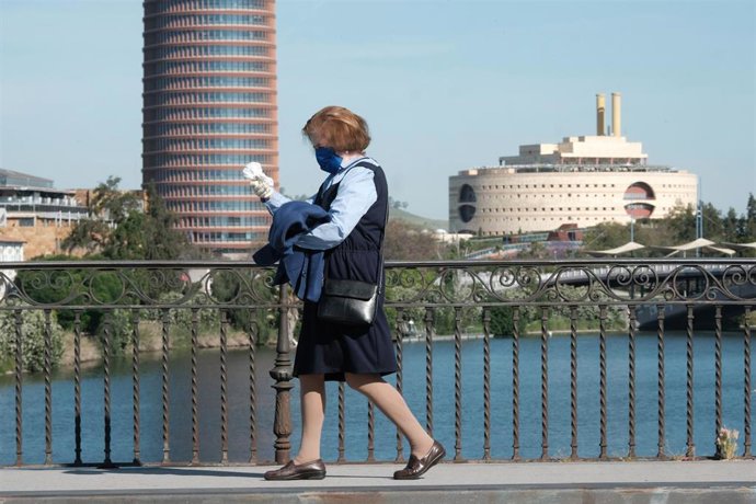 Una mujer pasea por el puente de Triana con el Paseo de la O al fondo