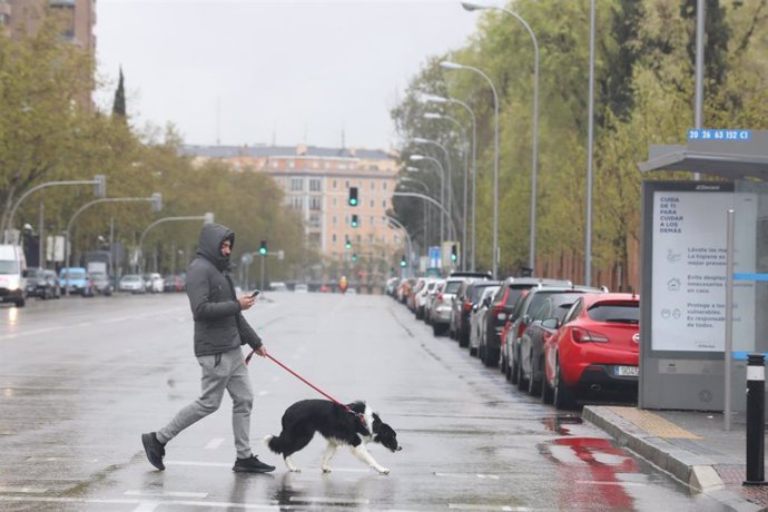 Un joven pasea un perro por el centro de la capital donde las temperaturas han bajado estrepitosamente durante el segundo día de la entrada en vigor de la limitación total de movimientos salvo de los trabajadores de actividades esenciales, medida adopta