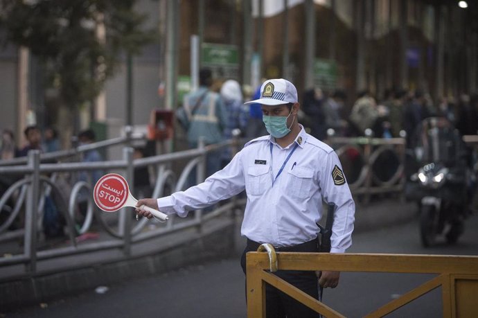 Un policía con mascarilla controla el tráfico en Teherán
