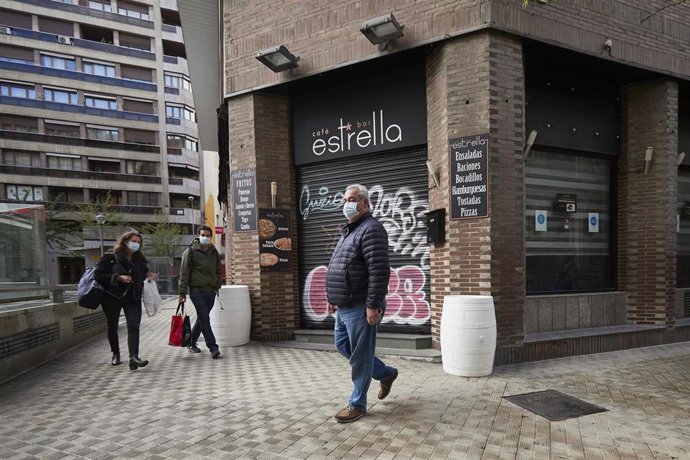 Transeúntes pasean por una calle de Pamplona protegidos con mascarilla debido a la crisis sanitaria del Covid-19, en Pamplona