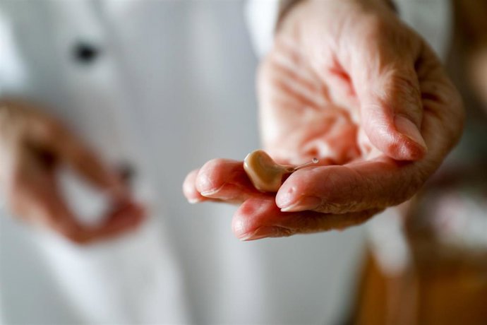 Una mujer muestra su audífono en el salón de su domicilio. En Madrid (España) a 12 de junio de 2020.