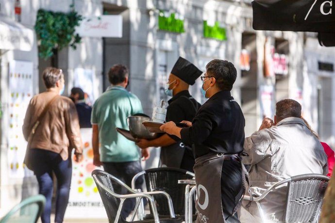 Dos camareros trabajan en una de las terrazas ubicadas en el Paseo del Prado, vía peatonalizada durante este fin de semana, en Madrid