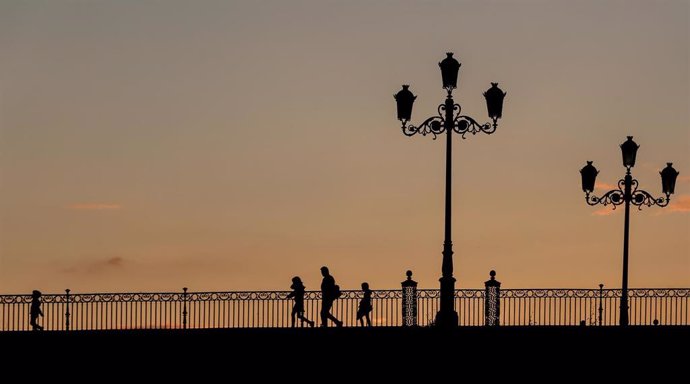 Un padre con sus hijos pasando al atardecer por el Puente de Triana. Sevilla a 28 de abril del 2020