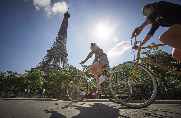 Una persona con mascarilla en bicicleta cerca de la Torre Eiffel de París, Francia