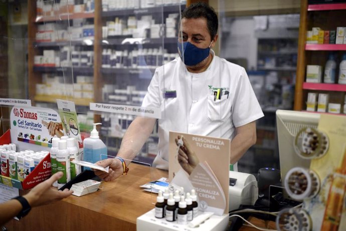 Un farmacéutico entrega a un cliente una de las mascarillas KN95 que ha recibido en su farmacia, en Madrid (España), a 30 de septiembre. Hoy era la fecha límite fijada por el Gobierno para dejar de comercializar equipos de protección individual (EPI) si