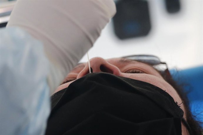 Un sanitario practica una prueba PCR a una mujer.