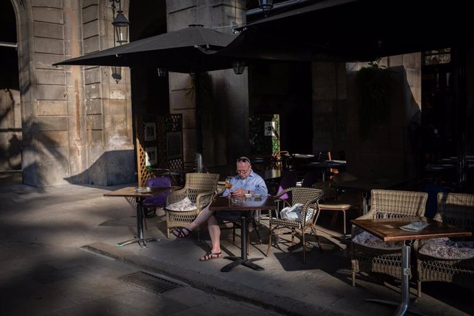 Un hombre consulta su teléfono móvil en la terraza de un bar en Barcelona, Cataluña (España) a 14 de octubre de 2020. La Generalitat ha anunciado hoy en rueda de prensa las nuevas medidas que entrarán en vigor la medianoche del jueves 15 de octubre por 