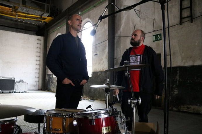 Marc Sempere i El Niño de Elche conversen al davant d'una bateria a la fbrica de l'Annima de Manresa. Imatge publicada el 15 d'octubre de 2020. (Horitzontal)