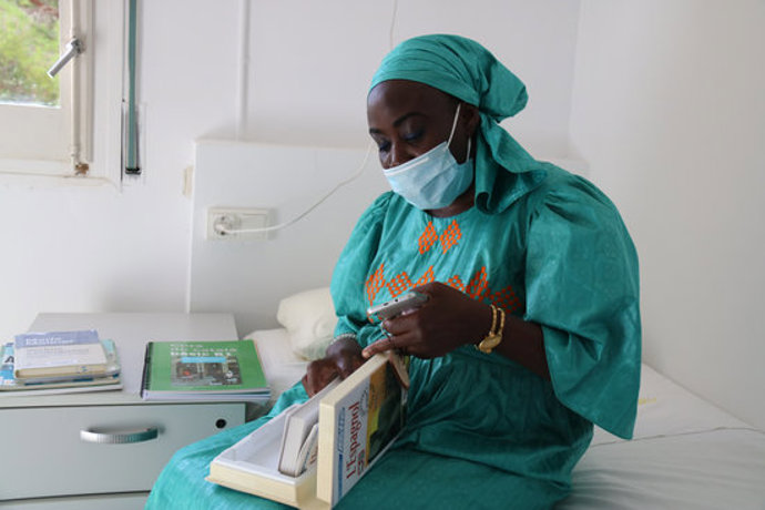 Sina Ndiaye, usuria del Centre Residencial dInclusió La Llavor per a dones sense llar, a la seva habitació fullejant un llibre. 15 d'octubre del 2020. (Horitzontal)