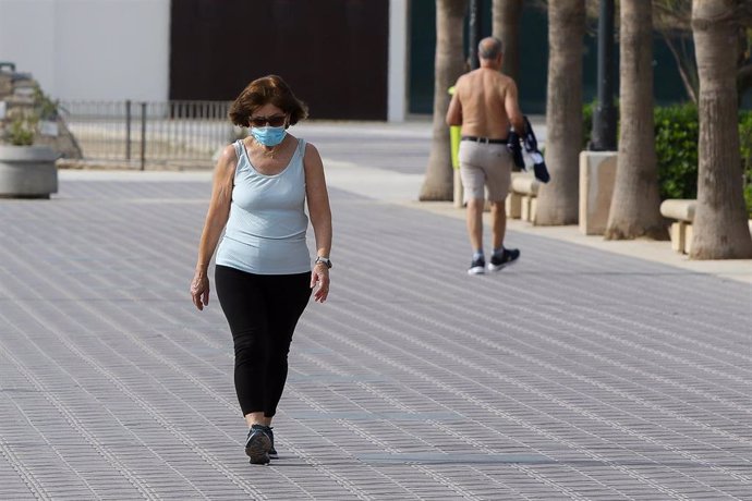 Una mujer con mascarilla pasea por la playa de la Malvarrosa