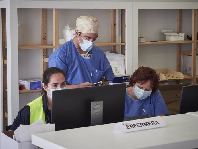 Trabajadores sanitarios protegidos atienden a los pacientes que acuden para realizarse una extracción de muestras en el recinto ferial REFENA de Pamplona 